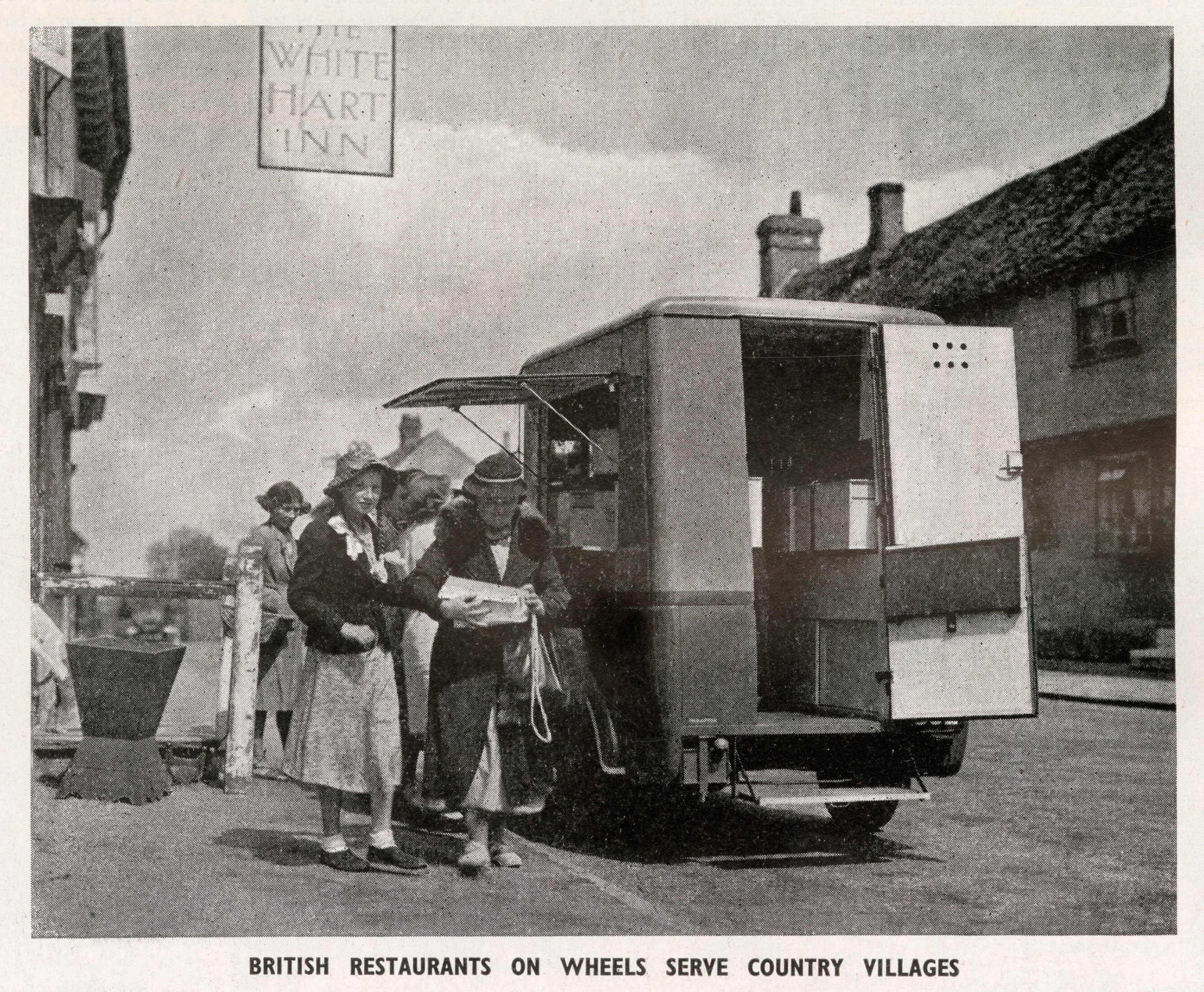 Several customers gather at a mobile canteen van in a residential street in the 1940s.
