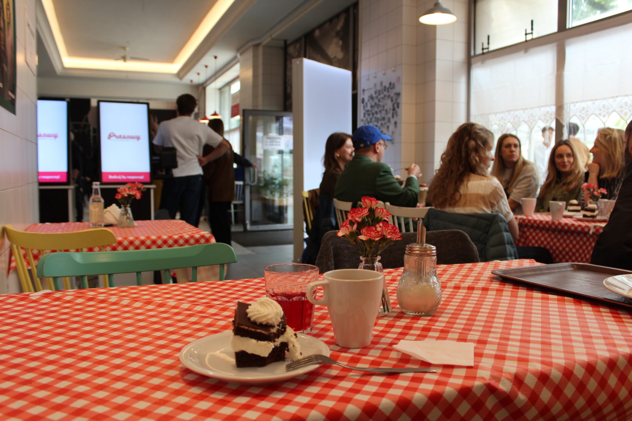 Cake and juice on table, with group of friends chatting at the next table