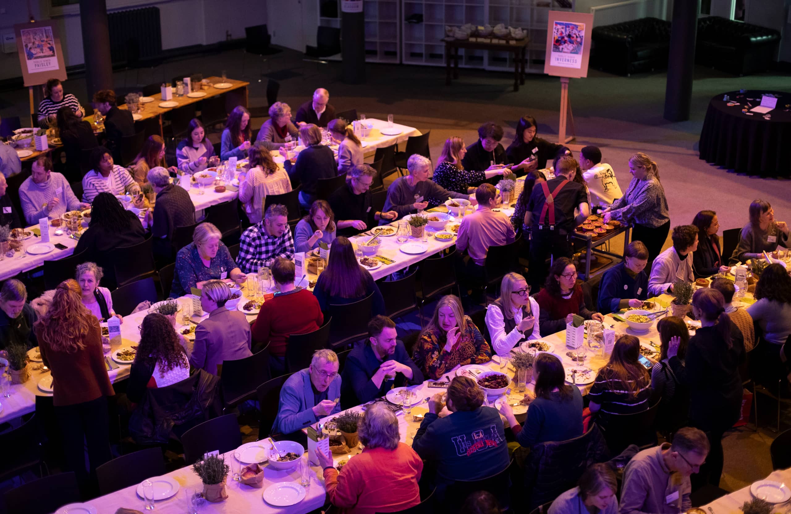 People eating together at long tables in a conference hall